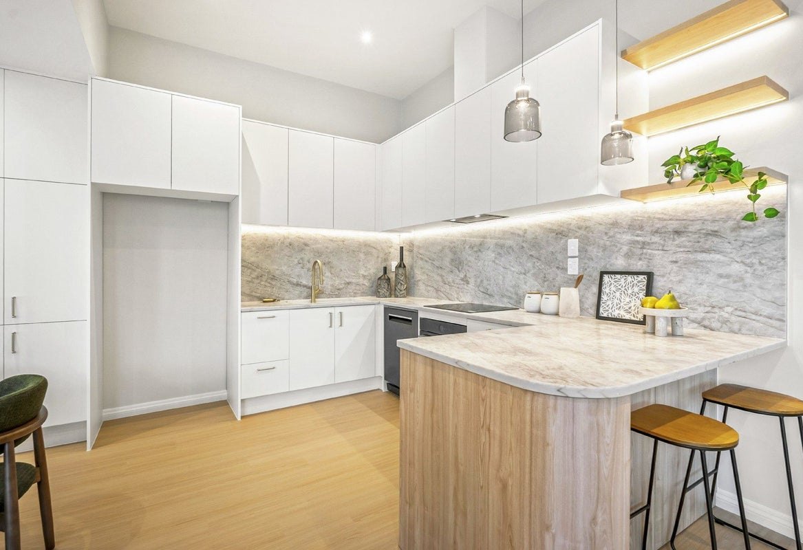 White kitchen with timber-clad curved peninsula and lit floating shelves